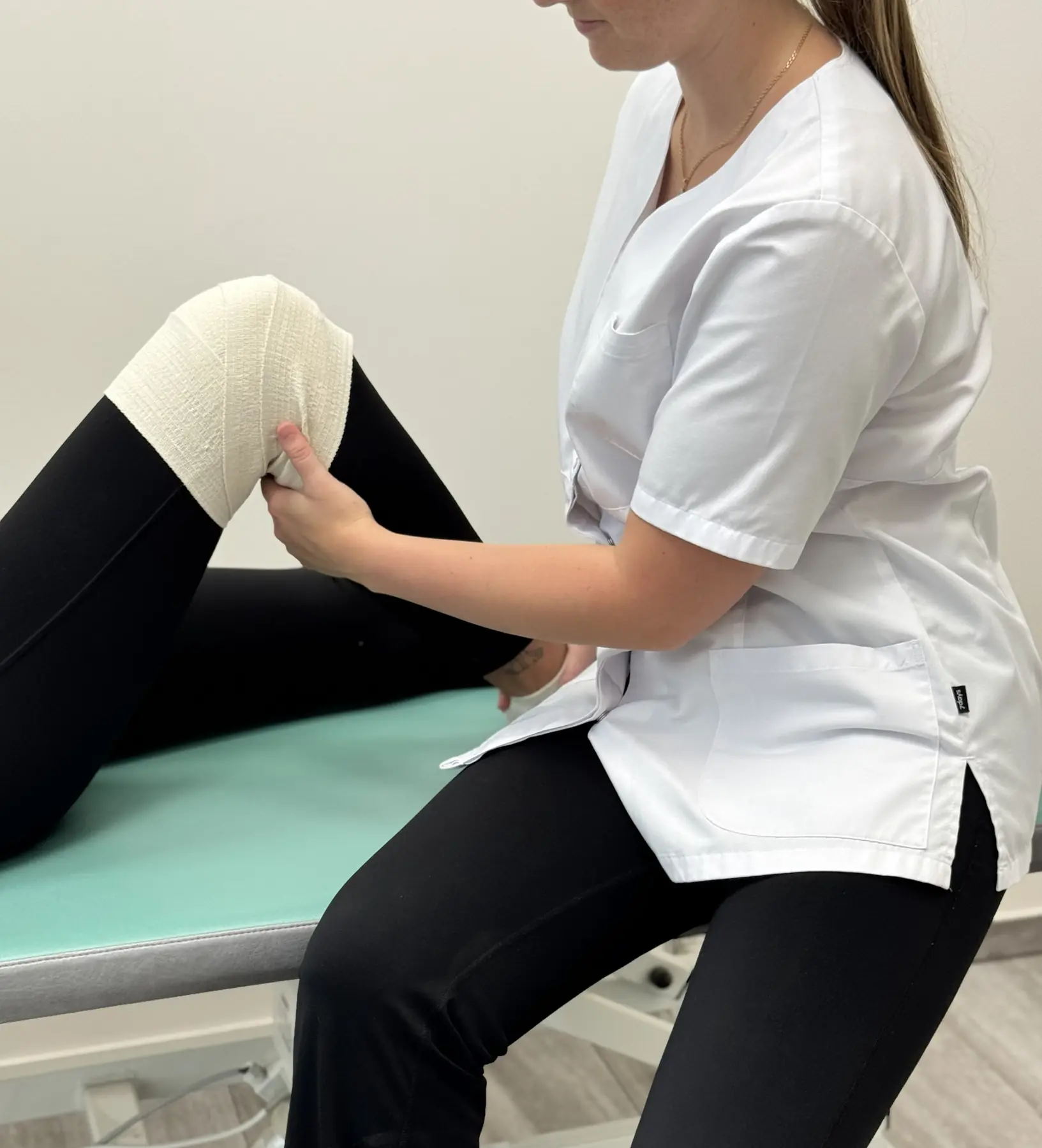 A physiotherapist assesses and supports a patient's knee movement